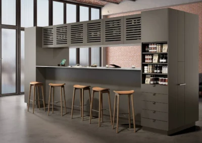 Cocina gris industrial con despensa columna giratoria abierta, muebles con lamas y techo de ladrillo visto tipo loft