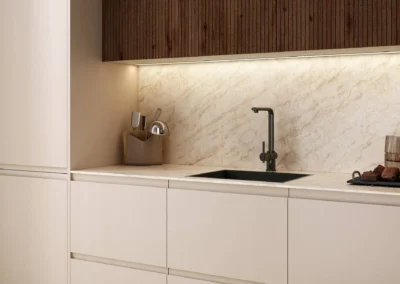 Detalle de zona de fregadero con frentes beige mate, salpicadero de mármol iluminado con LED y grifo negro mate