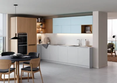 Cocina lineal blanca y madera con muebles altos azul celeste, horno doble columna, estantes abiertos y mesa de comedor redonda