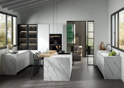 Cocina blanca con isla de porcelánico efecto mármol calacatta, vitrina iluminada y puerta corredera de cristal