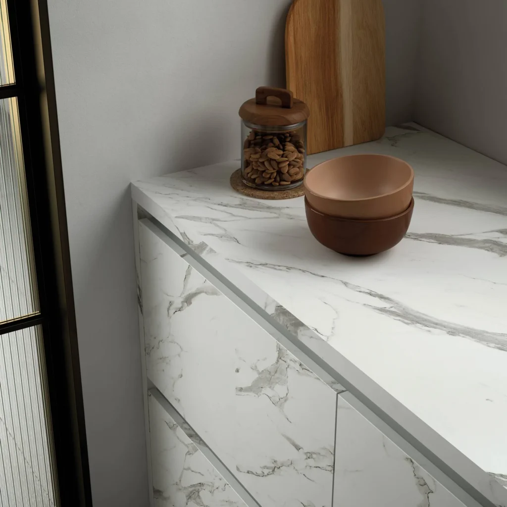 Detalle de encimera y frentes de cocina en porcelánico efecto mármol blanco calacatta con tirador integrado